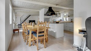 A spacious kitchen with wooden furniture, a central island, and a staircase leading to an upper level.
