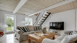 A living room with a sofa, coffee table, TV, and a staircase.