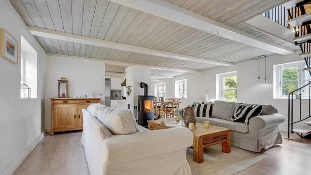 A spacious living room with a fireplace, a sofa, a coffee table, and a dining area.