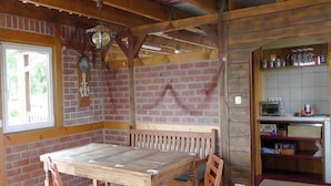 A rustic wooden dining area with a brick wall, a wooden bench, and a table. - Peeneblick - Reusenhof on the lagoon (Usedom)
