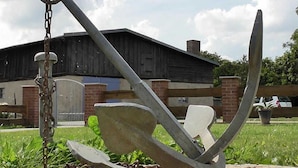 A large anchor sculpture outdoors with a building in the background. - Peeneblick - Reusenhof on the lagoon (Usedom)