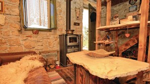 A rustic stone-walled room with a stone fireplace, a wooden bench, and a woven basket on the hearth. - Awesome home in Crkvice with house sea view (Crkvice)