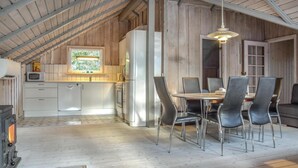 A rustic kitchen with a wooden ceiling, a dining area with metal chairs, and a large window. - Cozy home in Ringkøbing with sauna (Ringkøbing)