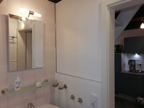A modern bathroom with a glass shelf holding toiletries, a toilet, and a mirror.