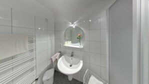 Een moderne badkamer met een wit wastafelmeubel, toilet en handdoekhouder.