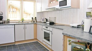 Una cucina moderna con mobili bianchi, un forno a microonde, un forno e un lavello. Sul bancone si trovano un calendario e un libro.