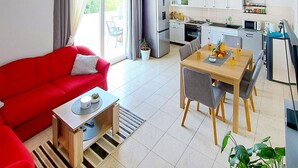 A modern living room with a red sofa, a wooden coffee table, and a dining area with a wooden table and grey chairs. - Beautiful home in Blizina Gornja (Blizina Gornja)