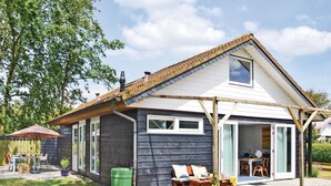 Een huis met twee verdiepingen, een donkere gevel, een schuin dak en een klein balkon.