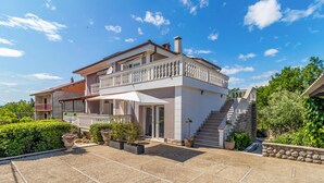 Ein zweistöckiges Haus mit Balkon, Treppe und Garten.