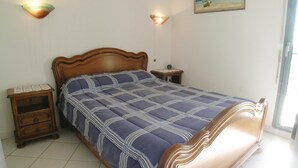 Une chambre à coucher avec un lit en bois, une table de chevet et une lampe fixée au mur.