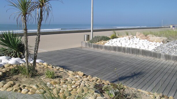 Une terrasse en bois offrant une vue sur la plage et l’océan.