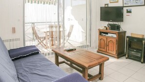Un salon comprenant un canapé, une table basse en bois, un téléviseur et un meuble.