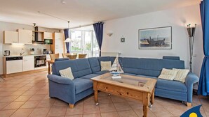 A modern living room with a blue sofa set, a wooden coffee table, and a kitchen in the background. - Villa beach pearl, Apt. 19 - Villa beach pearl, apt 19. (Heringsdorf)