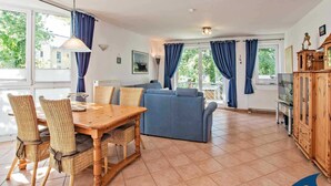 A spacious living area with a dining table, wicker chairs, a blue sofa, and a wooden cabinet. - Villa beach pearl, Apt. 19 - Villa beach pearl, apt 19. (Heringsdorf)