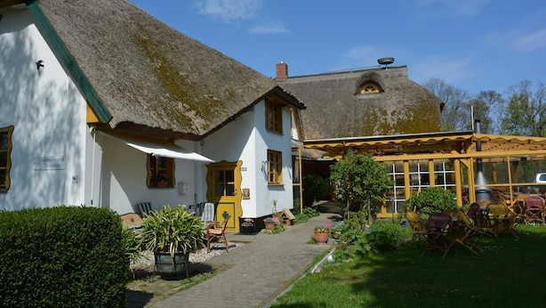 A traditional building with a thatched roof, a covered outdoor seating area, and a pathway leading to the entrance. - 6 - "Up'n Hoff", Germany (Middelhagen)