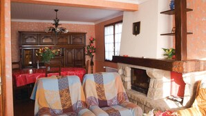 Una sala de estar acogedora con chimenea, un comedor con mantel rojo y un sofá estampado.