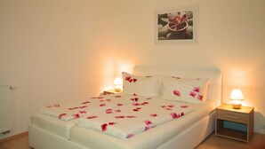 A neatly made bed with floral bedding, a bedside table with a lamp, and a framed picture on the wall.