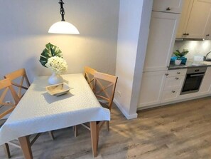 Uma área de jantar com uma mesa, cadeiras, um vaso com flores e uma luminária pendente.