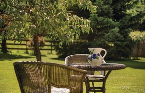 Relax in a serene outdoor setting with a wicker chair and small table.