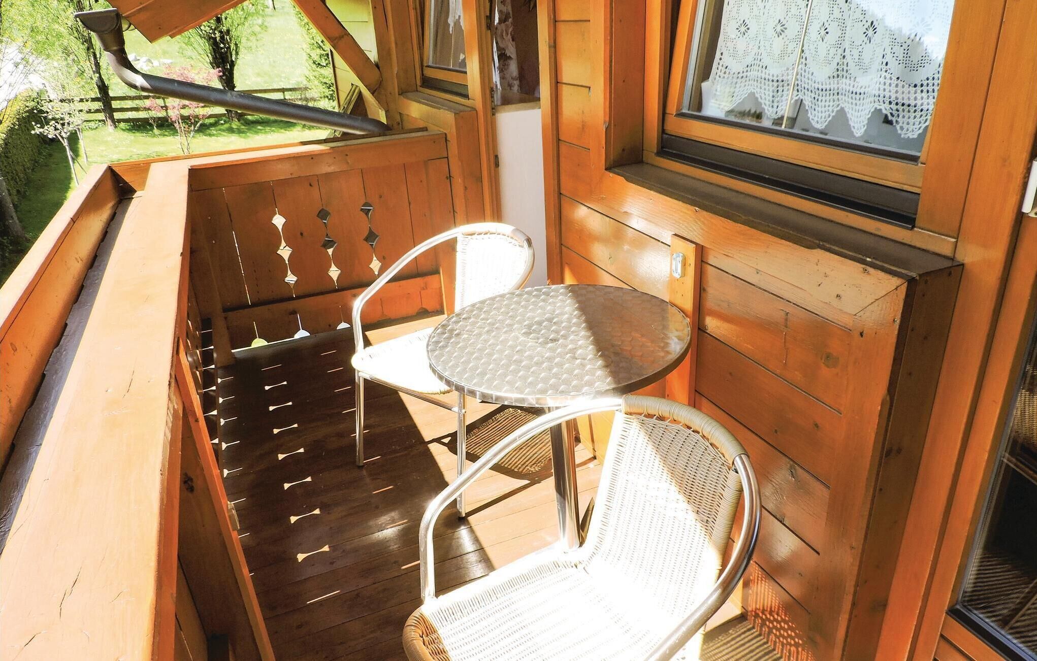 A wooden deck with two metal chairs and a small round table.