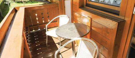 A wooden deck with two metal chairs and a small round table.