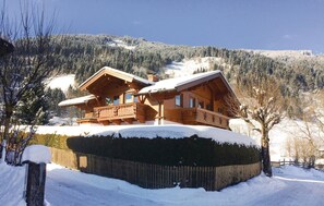Situated in a secluded mountainous area, this chalet offers a balcony with intricate railings and a steeply pitched roof.