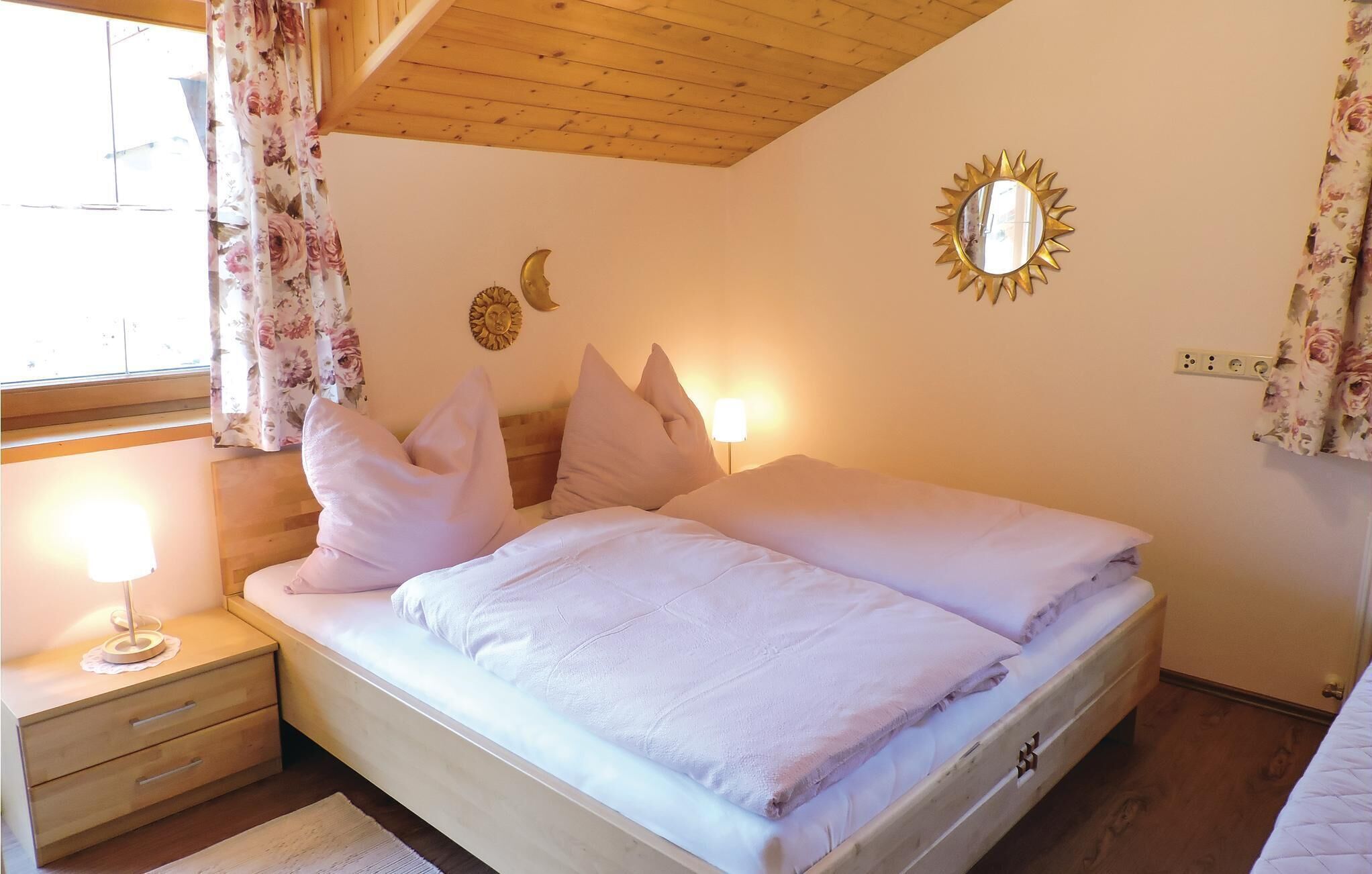 A neatly made bed with white linens, a wooden nightstand with a lamp, and a wall-mounted mirror.
