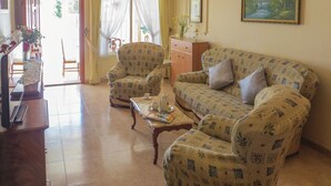 A living room with patterned sofas, a wooden coffee table, and a television. - Beach front home in Torrevieja with swimming pool (Torrevieja)