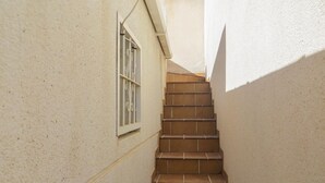 A narrow staircase with brown steps leading up to a door with a barred window. - Beach front home in Torrevieja with swimming pool (Torrevieja)