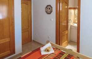 A hotel room with wooden doors, a towel on the bed, and a bathroom visible through an open door. - Beach front home in Torrevieja with swimming pool (Torrevieja)