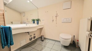 A bathroom with a sink, mirror, toilet, and a trash bin. - (207) 2-room apartment - Appartementhaus Strandstr. 16 (Kühlungsborn)