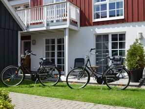 A building with a balcony, two bicycles parked outside, and a small table with chairs.