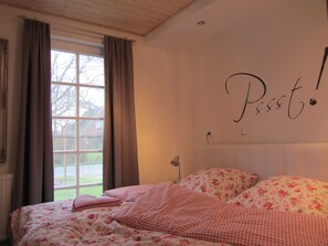 A bedroom with a bed, a window with curtains, and a wall with a sign.
