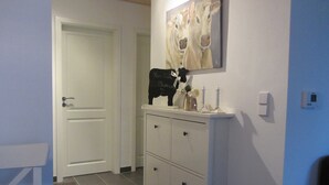 Ein Flur mit einer weißen Tür, einem weißen Schrank mit Schubladen und einem Bild von Kühen an der Wand.