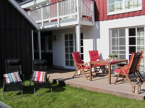 A deck with outdoor furniture, a table, and chairs.