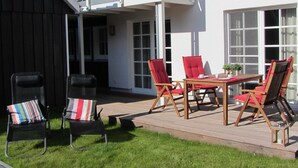 Eine Terrasse mit Tisch, Stühlen, einem kleinen Topfpflanzen und einer Laterne.
