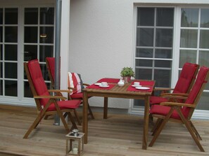 A wooden table with four chairs, a small potted plant, and a lantern on a wooden deck.