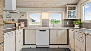 A modern kitchen with a large window, built-in cabinets, and a dishwasher. - Amazing home in Hvide Sande with sauna (Hvide Sande)