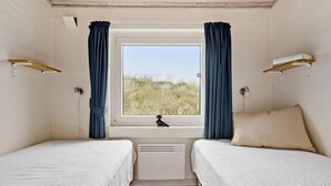 A room with two beds, a window with curtains, a radiator, and a lamp. - Amazing home in Hvide Sande with sauna (Hvide Sande)