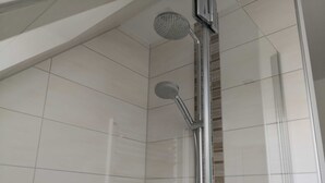 A shower with a handheld showerhead and a vertical rain showerhead, tiled walls, and a glass door. - Double room 05 (H) - guest house & beach hall (Ahrenshoop)