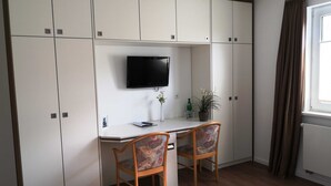 A compact room with a desk, two chairs, a television, and a potted plant. - Double room 05 (H) - guest house & beach hall (Ahrenshoop)