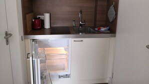 A compact kitchen with a built-in refrigerator, a sink, and a wooden countertop. - Double room 05 (H) - guest house & beach hall (Ahrenshoop)