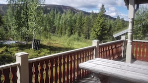 A wooden deck with a red railing overlooking a forested area with a mountain in the background. - Awesome home in Sälen with sauna (Sälen)