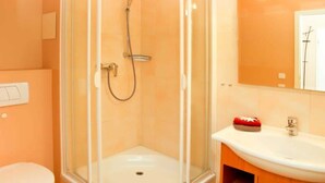 A bathroom with a glass-enclosed shower, a white sink, and a mirror. - (21) 3-room apartment - lake view - apartment house Atlantik (Kühlungsborn)