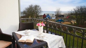 A balcony with a table set for two, overlooking a coastal area with colorful buildings. - (21) 3-room apartment - lake view - apartment house Atlantik (Kühlungsborn)