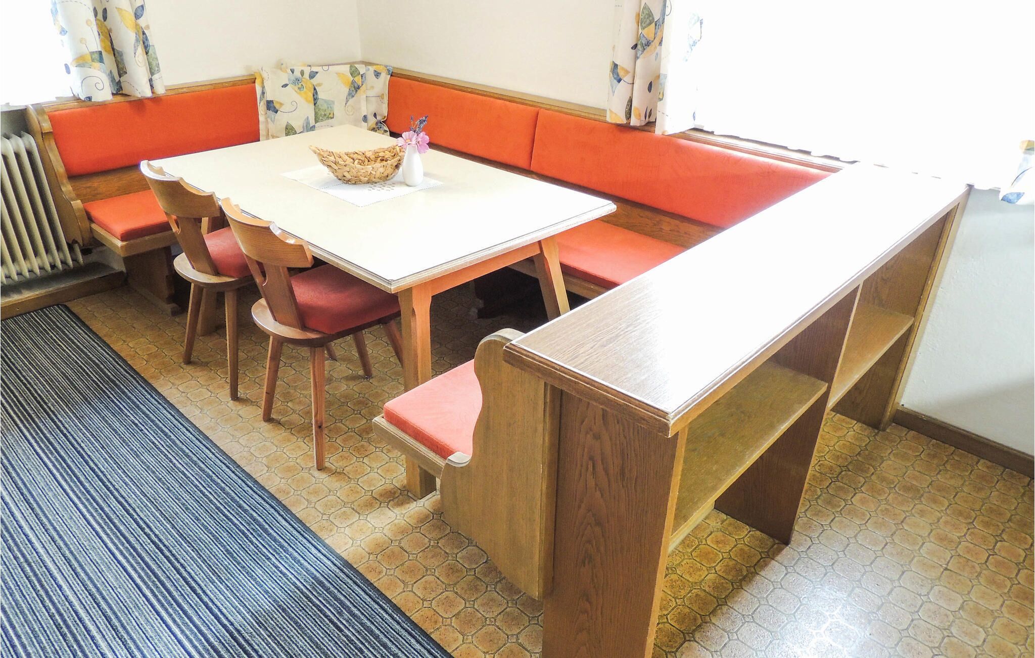A dining area with a wooden table, red cushioned benches, and a woven basket on the table.