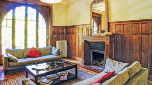 A cozy living room with a fireplace, wooden paneling, and a large mirror.