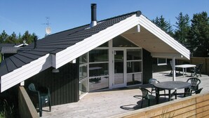 A modern house with a sloped roof, large windows, and a deck with outdoor furniture. - Amazing home in ålbæk with WiFi (Ålbæk)