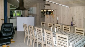 A modern kitchen with wooden cabinets, a central island, and a dining area with a table and chairs. - Amazing home in ålbæk with WiFi (Ålbæk)