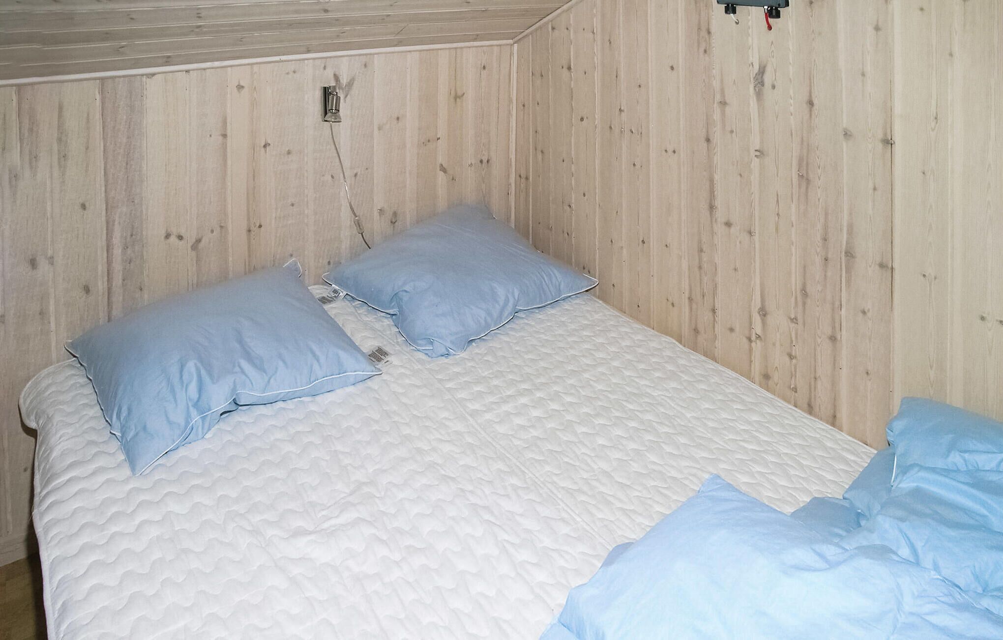 Uma cama de solteiro com colchão branco acolchoado e duas almofadas azuis.